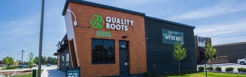Full exterior storefront of Quality Roots Madison Heights dispensary showcasing contemporary design, large branded sign, landscaped entrance, and John R Road location